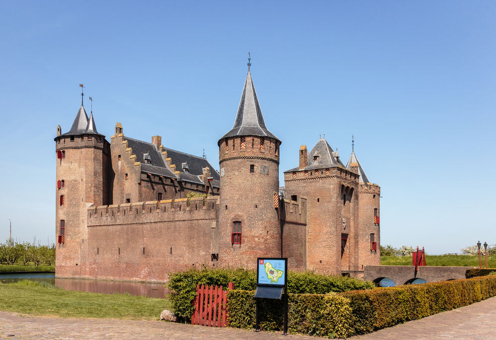 Het Muiderslot met torens en slotgracht tegen een blauwe lucht